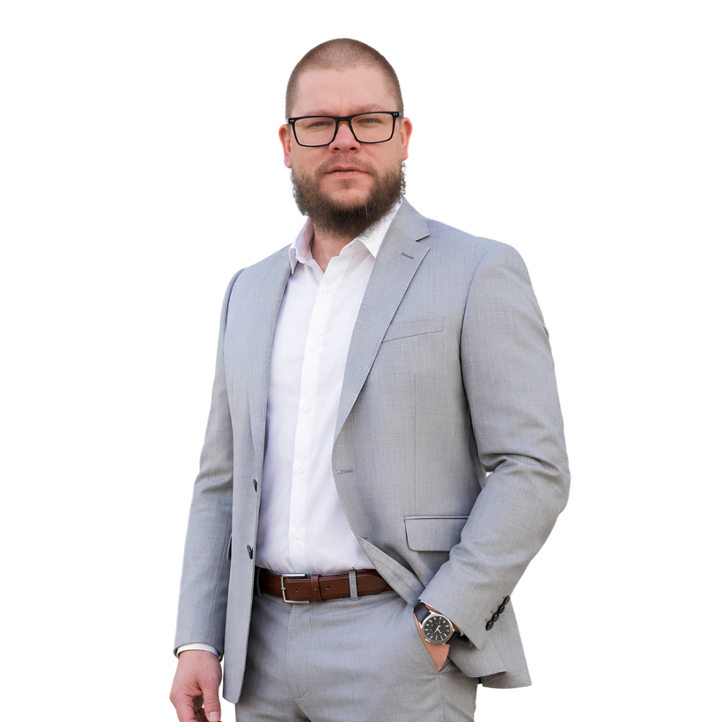 mężczyzna z brodą w okularach, w szarym garniturze